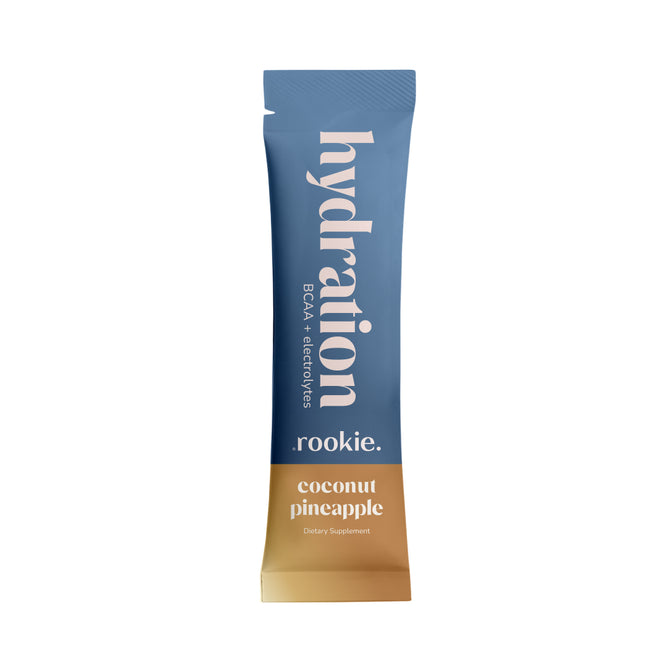 A blue and tan stick pack labeled Hydration Coconut Pineapple - Sample from Rookie Wellness, this dietary supplement features a refreshing coconut pineapple flavor and provides essential amino acids and electrolytes for optimal BCAA hydration.
