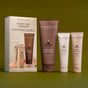 Three Innersense Organic Beauty Radiant Skin Ceremony products—a scrub, Awaken Body Wash, and lotion—stand beside their box packaging against an olive green background.