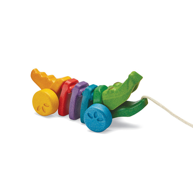 The PlanToys Rainbow Alligator is a colorful pull toy with segmented rainbow body parts that encourages gross motor skills. Made from sustainable wood, it features a front string and is beautifully designed for eco-friendly play.