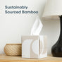 A box of Reel Premium Bamboo Facial Tissues (60 3-ply tissues per box), made from sustainably sourced bamboo, sits on a table beside a woven basket and lamp. The words "Sustainably Sourced Bamboo" appear above the tissue box.