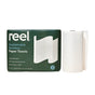 A package of Reel Premium Bamboo Paper Towels—135 2-ply sheets per roll—sits beside a single white roll, with green packaging and white text emphasizing these sustainable, tree-free towels.