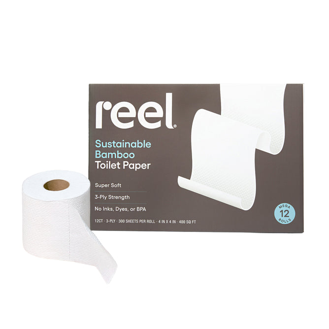 A box of Reel Premium Bamboo Toilet Paper sits behind a roll, showcasing “Super Soft,” “3-Ply Strength,” and “No Inks, Dyes, or BPA.” Tree-free and septic-safe, the box contains 12 mega rolls with 300 3-ply sheets each.