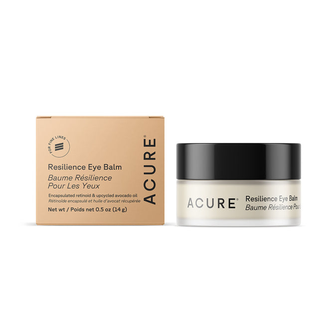A small beige box labeled Acure Resilience Eye Balm stands next to an open jar of the same product with a black lid and bilingual English-French text; both are formulated to target dark circles.