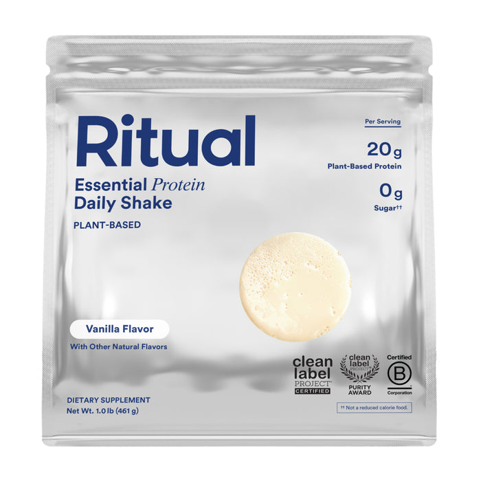 A silver pouch of Ritual Essential Protein Daily, a vegan vanilla protein powder with 20g protein and 0g sugar per serving. The packaging displays certification logos and an image of the protein powder on the front.