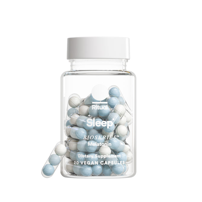 A clear bottle labeled Ritual Sleep contains 20 blue and white vegan capsules for natural sleep support. This dietary supplement by Ritual features melatonin to help promote restful sleep.