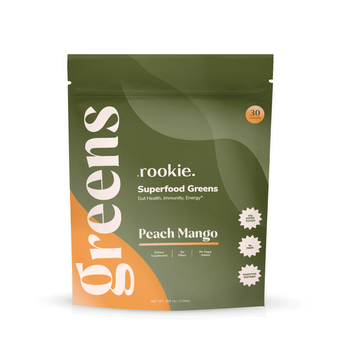 A resealable green and orange pouch labeled Rookie Wellness Greens + Superfood in Peach Mango flavor, with icons for dietary supplement, no sugar added, gut health support, probiotics, and 30 servings of daily greens.