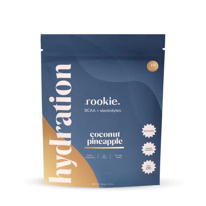 A blue and gold Rookie Wellness pouch labeled "Hydration Support + Electrolytes with BCAA" in white text, showcasing coconut pineapple flavor. Features icons for no sugar added and dietary supplement—your ideal electrolyte boost.