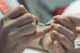Close-up of hands as one person applies Rugged Beautys Lavender Nail Bed Healer to anothers fingernails, focusing on the brush and product application.