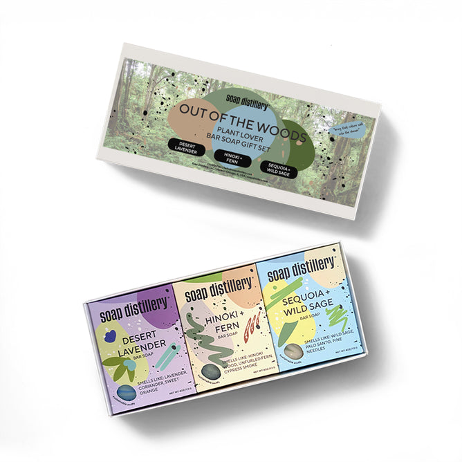 Soap Distillery’s Out of the Woods Three Soap Gift Set features three nature-inspired bar soaps—Desert Lavender, Hinoki + Fern, and Sequoia + Wild Sage—in pastel packaging decorated with plant illustrations.