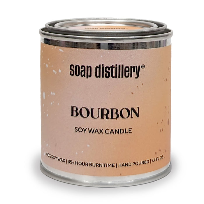 A metal tin labeled Soap Distillery Soy Wax Candle. This 100% soy wax, paraffin-free candle is hand poured, clean burning, has a 35+ hour burn time, contains 12 fl. oz., and features a tan speckled label.