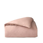 A neatly folded blush pink comforter with a smooth texture, set against a plain white background, highlights the elegance of the Coyuchi Organic Crinkled Percale™ Duvet Cover—crafted from breathable, luxurious organic cotton.