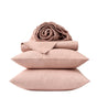 Two pink pillows stacked with a folded and rolled pink quilt on top, all set against a plain white background—an inviting arrangement that highlights the Coyuchi Organic Crinkled Percale™ Sheet Set, crafted from breathable GOTS certified cotton for ultimate comfort.