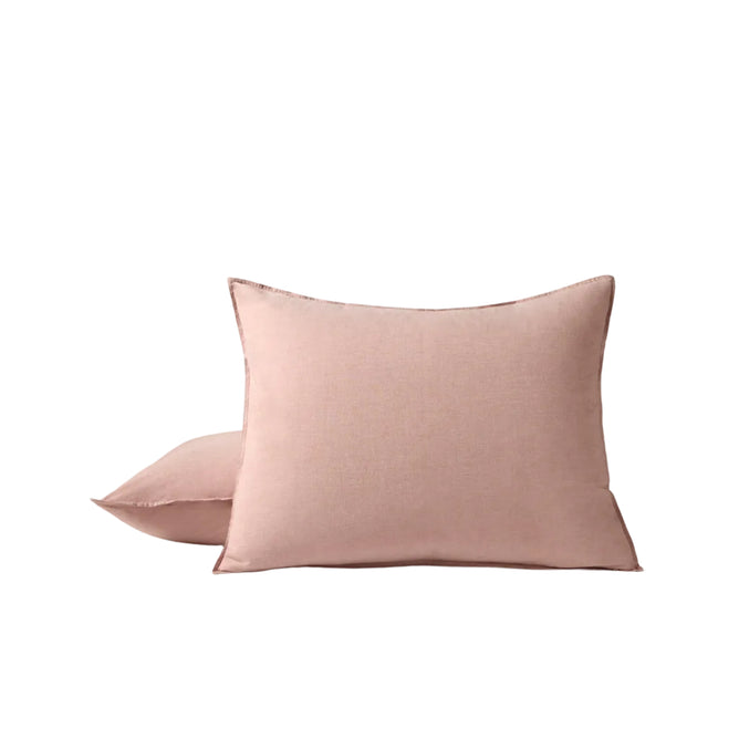 Two square, blush pink throw pillows are displayed against a plain white background, with one upright and the other slightly behind and lying down—perfect accents for breathable bedding or pairing with the Coyuchi Organic Crinkled Percale™ Sham.