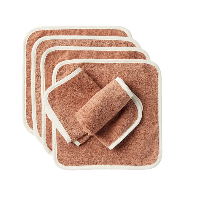 A set of six Cloud Loom™ Organic Baby Wash Cloths by Coyuchi—brown, square-shaped, and edged in white—are displayed overlapping one another, with one cloth rolled up and resting on top. Crafted from soft and absorbent organic cotton, these durable washcloths are perfect for gentle baby care or everyday cleansing.