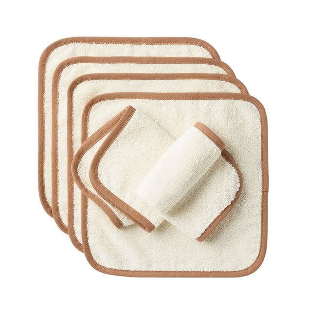 A set of six Cloud Loom™ Organic Baby Wash Cloths by Coyuchi, crafted from ultra-soft, cream-colored organic cotton with brown trim, are stacked and slightly offset against a plain white background. One cloth is rolled and placed on top, making them perfect for baby care.
