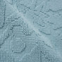 Close-up of the Coyuchi Wildflower Organic Bath Rug, featuring a textured light blue surface with raised patterns and a grid-like weave. Crafted from organic cotton, the bath rug appears soft and plush, with a gently folded area in the center evoking its absorbent and luxurious quality.