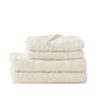 A neatly folded stack of three Coyuchi Wildflower Organic Bath Towels, featuring a subtle cream-colored botanical pattern, sits on a white surface against a plain white background, showcasing the natural beauty and softness of each absorbent towel.