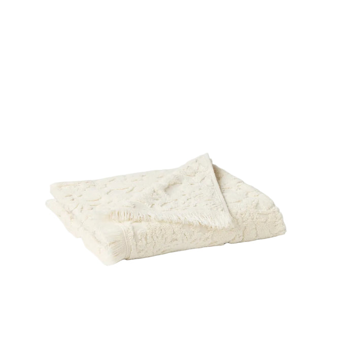 The Coyuchi Wildflower Organic Bath Towel, crafted from cream organic cotton with a tufted floral texture and fringe trim, is shown folded on a white background.