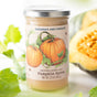 A jar of Savannah Bee Company Pumpkin & Winter White Whipped Duo, with festive pumpkin-themed packaging, is paired with pumpkin leaves and slices—a perfect autumn-inspired seasonal treat.