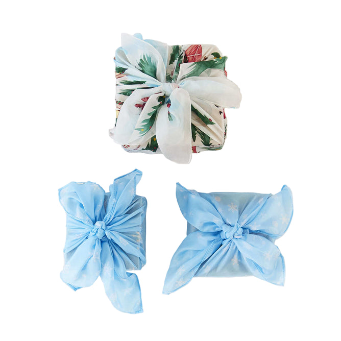 Three gifts wrapped in Sarahs Silks Winter Wonderland Reusable Gift Wrap Furoshiki Set—two in light blue and one in floral-patterned silk, finished with a white ribbon—are neatly arranged on a white background.