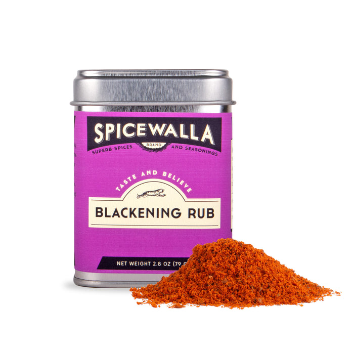 A silver tin of Spicewalla Blackening Seasoning with a purple label is displayed beside a small heap of spicy, orange-red blend on a white background.