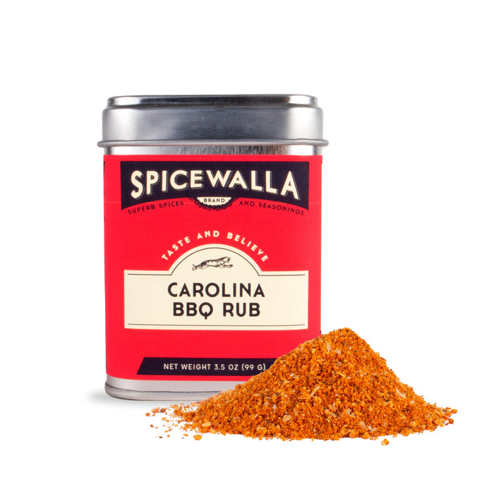 A tin of Spicewalla Carolina BBQ Rub with a bright red label sits next to a small pile of the orange and brown rub, inspired by classic Carolina BBQ sauce flavors, displayed on a white background.