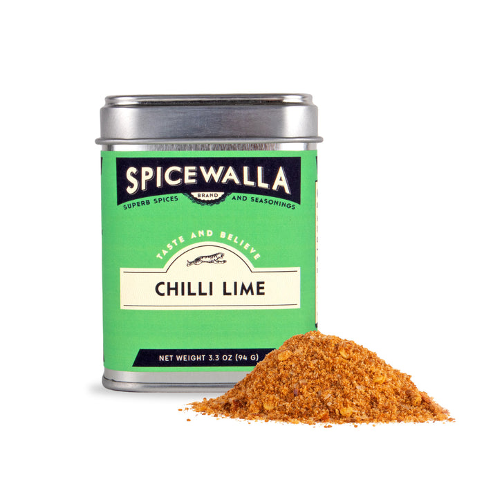 A tin of Spicewalla Chilli Lime Seasoning with a green label sits beside a small pile of spicy, tangy seasoning powder on a white background—a flavorful meal-time upgrade.
