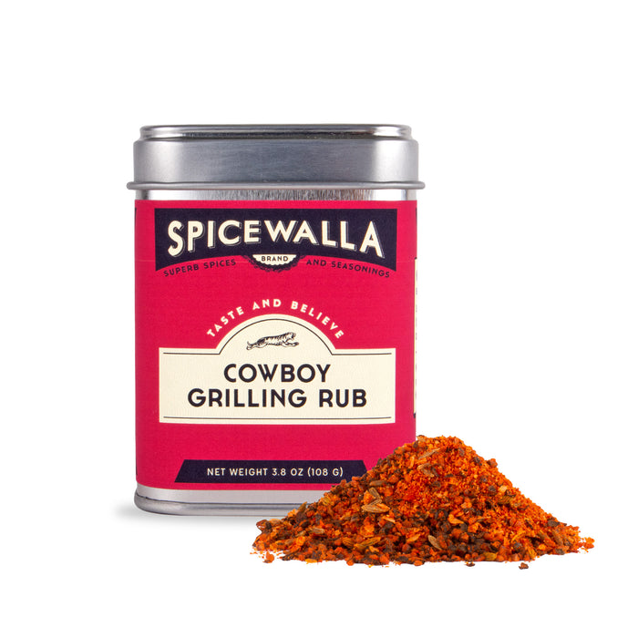 A 3.8 oz (108g) Spicewalla Cowboy Grilling Rub tin with a red label sits next to a small heap of the smoky, reddish-orange blend—perfect for adding bold, grilled flavor to your favorite dishes.