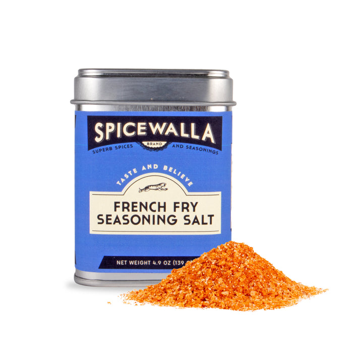 A Spicewalla French Fry Seasoning Salt tin with a blue label sits by a pile of orange and yellow seasoning, offering a zesty way to add extra flavor to your fries.
