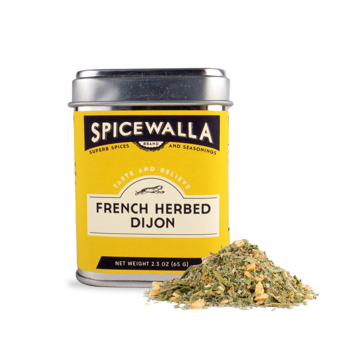 A yellow Spicewalla French Herbed Dijon tin with a metal lid sits beside dried herb blend, featuring tarragon hints. The label displays black and white text with decorative accents.