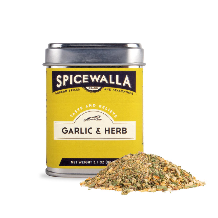 A yellow Spicewalla tin of Garlic & Herb Seasoning sits beside a small pile of the blend, displaying dried herbs, spices, and orange peel flecks for vibrant flavor.