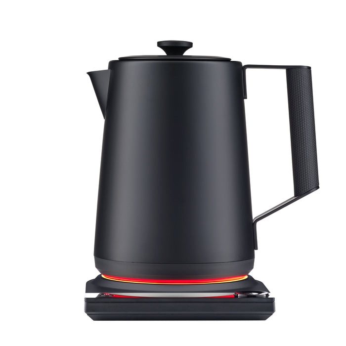 The Saki Luna Stainless Steel Electric Kettle Pro, featuring a sleek matte black design, rests on its base, which emits a red glow at the bottom to indicate that the electric kettle is powered on.