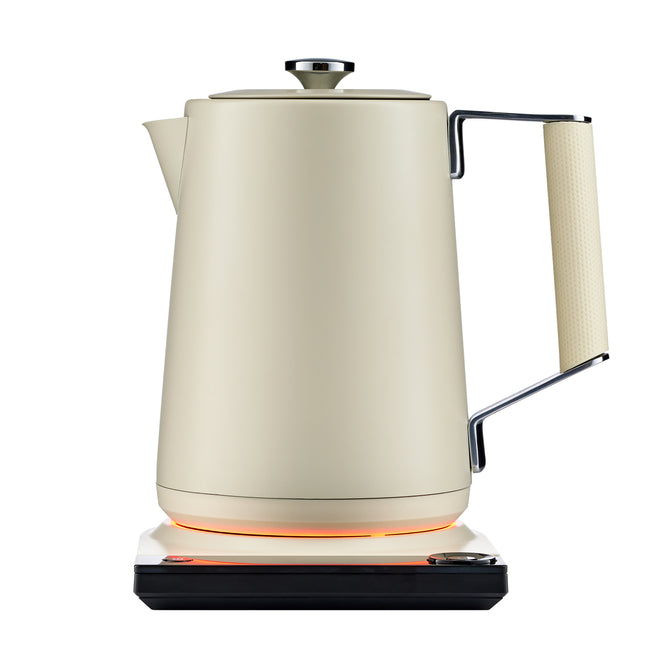 The Saki Luna Stainless Steel Electric Kettle Pro, in cream, features temperature control and a textured handle. It sits on a matching square base with an orange light, showing it’s powered on, against a white background.