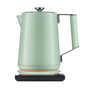 The SAKI Luna Electric Kettle Pro in matte green, featuring a textured handle, rests on a sleek white and black base, with an illuminated orange ring showing it’s powered on. Designed for convenience, its preset programs and adjustable temperature settings ensure perfect brewing for your favorite drinks. The background is plain white.