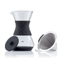The Saki Pour-Over Glass Coffee Maker features borosilicate glass, a black silicone grip, and comes with a matching black lid. A separate reusable coffee filter is placed beside it.