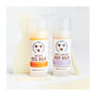 Two tubes from the Savannah Bee Company Heel Balm and Body Balm Gift Set stand upright on a white surface, labeled "Beeswax Heel Balm" and "Honey & Beeswax Body Balm." Pieces of beeswax are scattered around them, highlighting their role as a natural skin moisturizer. The labels show their scents: tangerine spearmint and rosemary lavender.