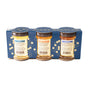 Three glass jars of honey—Orange Blossom Honey, Acacia Honey, and Lavender Honey—from Savannah Bee Company are arranged in front of a blue box labeled “Honey Artisanal Sampler Set” adorned with honeycomb designs. Each jar features a descriptive label showcasing the unique flavor notes of its variety.