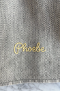 The Sawa - Moon Stone grey merino baby blanket in knit fabric with the name Phoebe embroidered in yellow cursive thread.