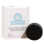 A round, black Scalp Care Conditioner Bar from Good Juju Body & Home is shown in front of a white box labeled with its name and ingredients—lavender and geranium—in both English and French.