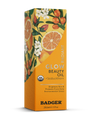 A box of Badger Balm Seabuckthorn Glow Beauty Oil, adorned with images of oranges and flowers. This biocompatible oil comes in yellow packaging with text highlighting its skin-brightening benefits and protection from environmental stress—an ideal choice for those seeking organic skincare solutions.
