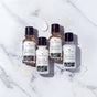 The Tree To Tub Relaxing Lavender Travel Essentials Set, featuring four travel-size bottles, is displayed on a white surface with small product smears nearby.