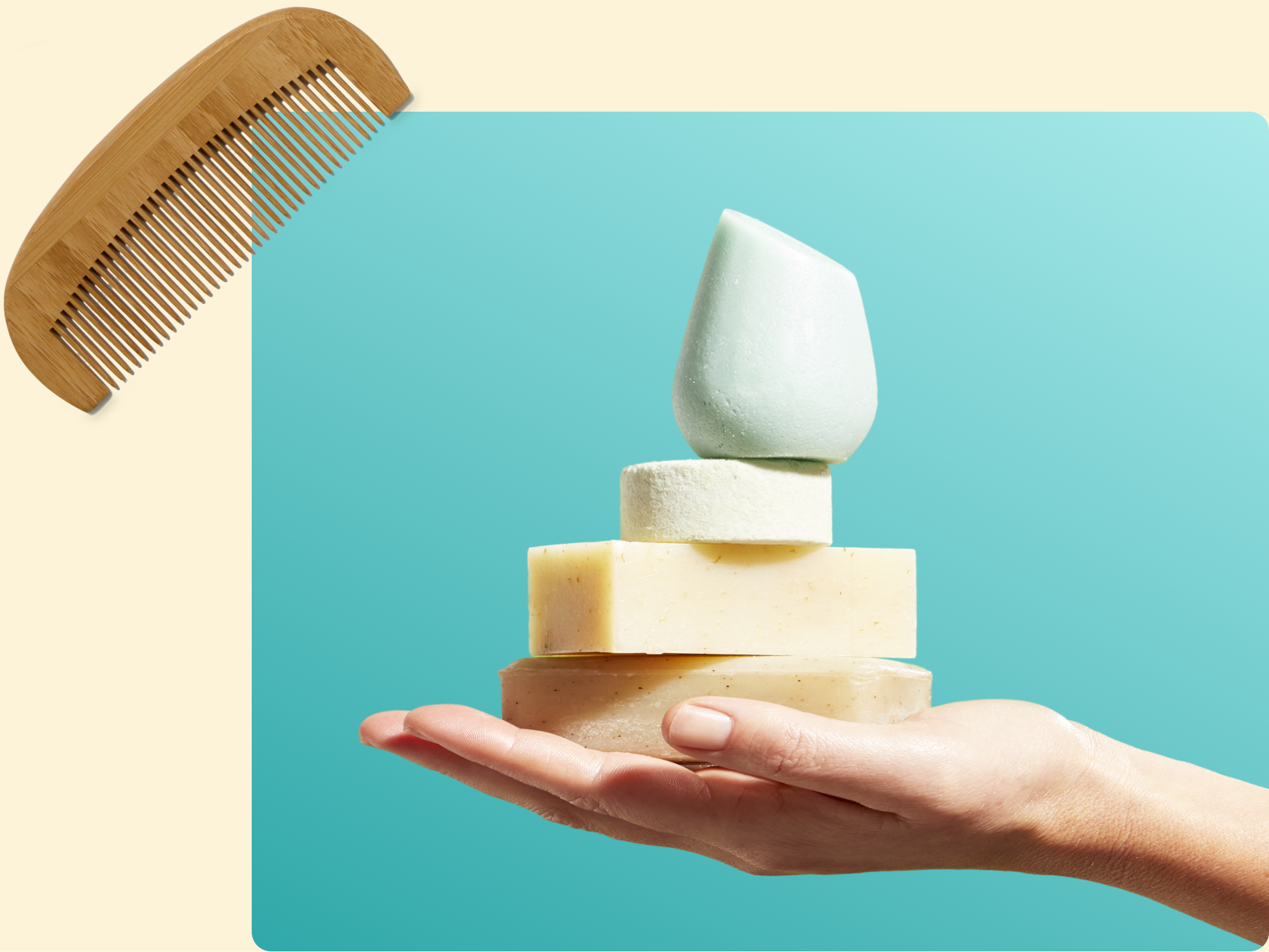 A hand holds three stacked solid shampoo and soap bars in different shapes and colors, with a wooden comb placed in the top left corner against a blue and beige background.