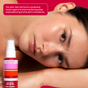 A woman with glowing skin rests her head on her arm beside a bottle of Shielded Beauty Face the Day Purifying Mist, a facial spray that purifies, provides antioxidant protection, and balances the skin’s microbiome.