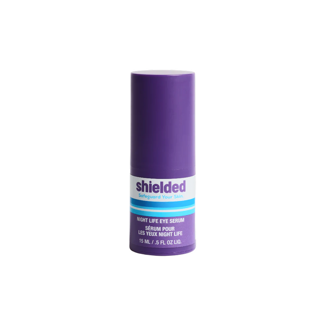 A purple bottle of Shielded Beauty Night Life Live Probiotic Eye Serum with white and blue labeling stands upright on a plain white background. The container holds 15 ml (0.5 fl oz) of overnight eye serum.
