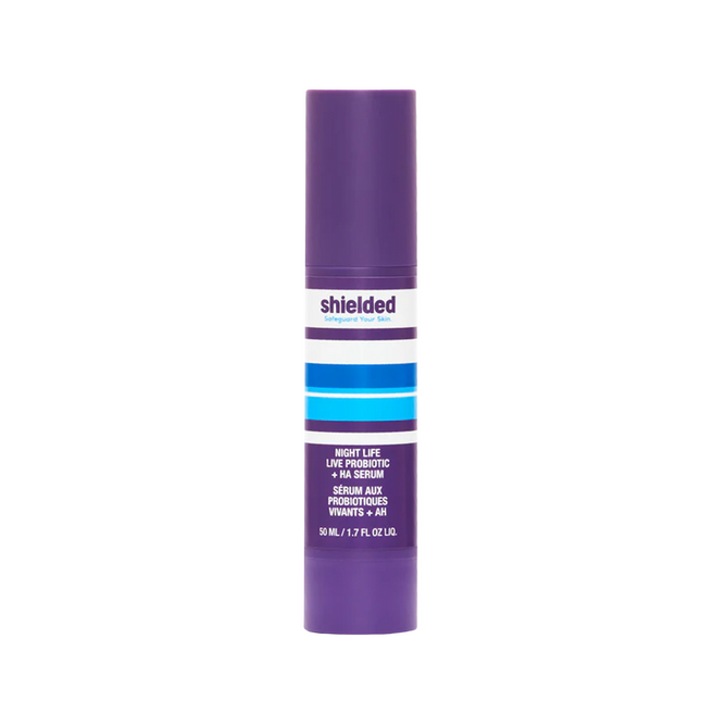 A purple bottle of Shielded Beauty Night Life Live Probiotic + HA Serum with a white label and blue stripes, containing 50 mL (1.7 fl oz) of this nourishing overnight probiotic serum.