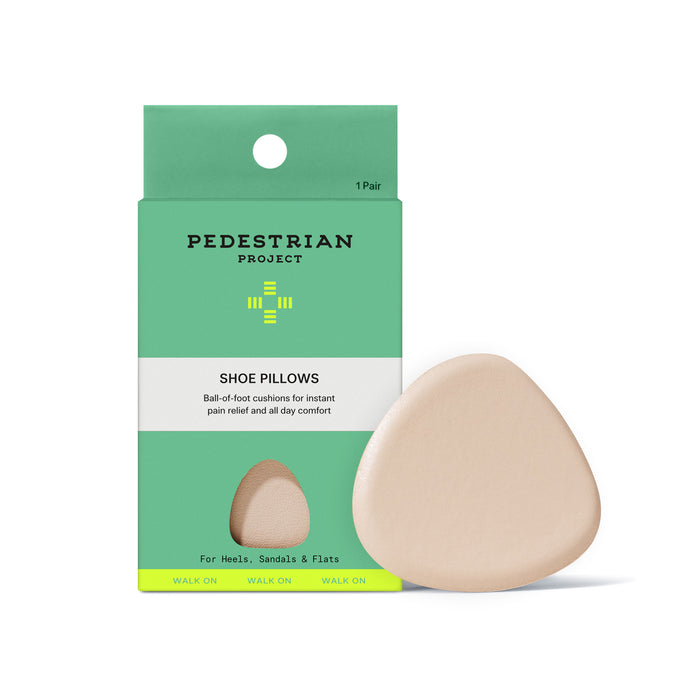 A pack of Pedestrian Project Shoe Pillows - Ball of Foot Inserts, with beige, triangular Eco-Bounce Foam cushions for comfort and pain relief. One insert is shown beside the brand’s green and white packaging.