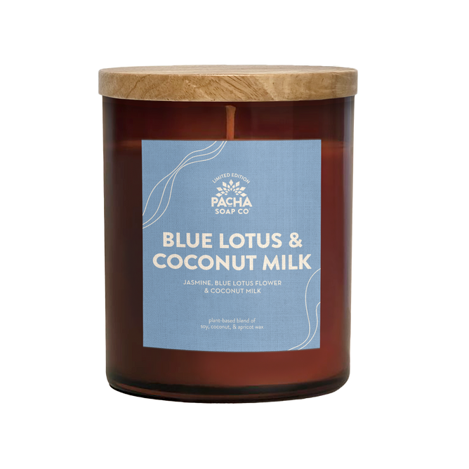 The Signature Candle - Blue Lotus & Coconut Milk by Pacha Soap Co. is a brown glass jar with wooden lid, featuring notes of jasmine, blue lotus flower, and coconut milk. Crafted with soy, coconut, and apricot wax for a premium burn.