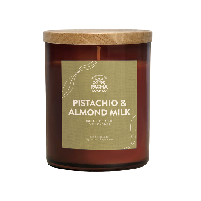 The Signature Candle - Pistachio & Almond Milk by Pacha Soap Co. comes in a brown glass jar with a wooden lid and green label, featuring a plant-based soy coconut apricot wax blend for a premium, clean burn.