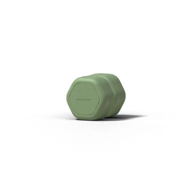 A small, green, hexagonal Skincare Duo Travel Container by Cadence with Moisturizer printed on the lid, shown on a white background.