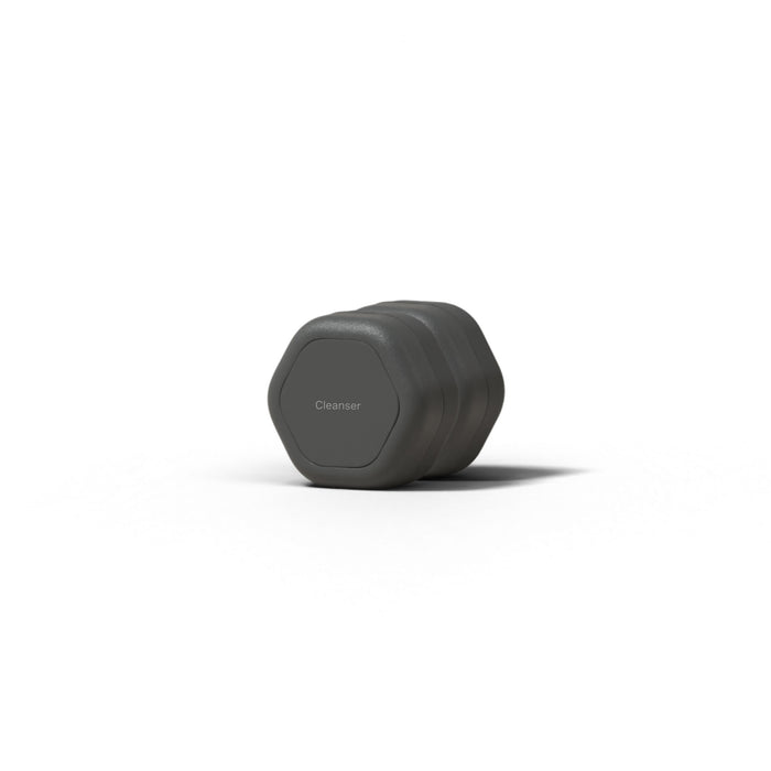 A dark gray, hexagonal Cleanser bar rests on a white surface with a shadow nearby—ideal for storing in your Cadence Skincare Duo Travel Containers or any TSA-approved travel case.
